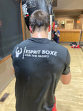 T-shirt de boxe Esprit Boxe noir en polyester technique, grand logo blanc dans le dos, porté devant un sac de frappe