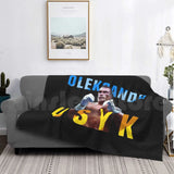 Plaid boxe Usyk noir drapé sur un canapé, lettrage bleu et jaune