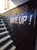 Sticker Never Give Up posé sur le mur d'une salle de sport