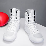 Chaussures de boxe noires à lettrage BOXING doré, tenues à la main