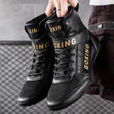 Chaussures de boxe noir et or tenues à la main, sangle scratch visible