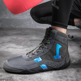 Chaussures de boxe grises portées à l'entraînement, gant de boxe rouge
