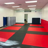 Salle de JJB équipée de tatamis vinyle lisse rouges et gris anthracite en damier, protection murale rouge