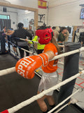 Jeune championne de boxe belge à l'entraînement avec les gants de sparring Esprit Boxe orange