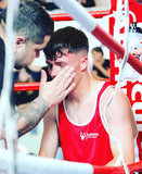 Boxeur en tenue de boxe amateur rouge Esprit Boxe entre les cordes du ring