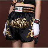 Short muay-thaï noir à lettrage thaï มวยไทย et ceinture à bandes dorées, porté