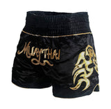 Short muay-thaï noir à lettrage MUAY THAI doré et flammes dorées, ceinture à liseré doré, vue de trois-quarts