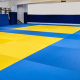 Dojo équipé de tatamis vinyle lisse bleus et jaunes, protection murale bleue et horloge de round