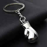 Porte-clés gant de boxe argent posé sur cuir noir, reflet du poli miroir