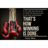 Tableau gants de boxe rouges suspendus a un poteau de bois et citation en capitales creme, detail de l'impression