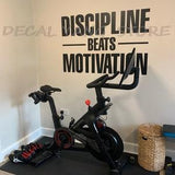 Sticker Discipline beats Motivation en vinyle sombre à côté d'un vélo d'appartement