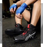 Chaussures de boxe anglaise noires portées, mains bandées de bleu