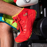 Chaussure de boxe rouge portée, short vert fluo et gant blanc