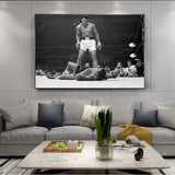 Tableau Ali vs Liston noir et blanc, Ali debout au-dessus de Sonny Liston, accroche dans une entree