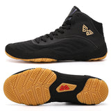 Chaussure de boxe noir et or de profil, logo doré en ailes