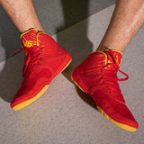 Chaussures de boxe rouge et or portées, semelle caramel au sol