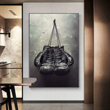 Tableau gants de boxe noirs suspendus devant un mur de beton, affiche dans un salon