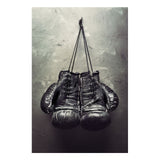 Tableau gants de boxe noirs suspendus devant un mur de beton, toile seule, sans cadre