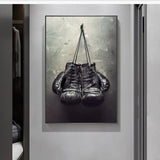 Tableau gants de boxe noirs suspendus devant un mur de beton