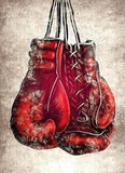 Tableau gants de boxe rouges laces suspendus sur fond creme, mise en situation murale